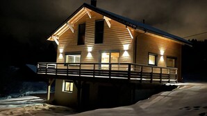 Une cabane en bois à deux étages, dotée d’un balcon, entourée de neige.
