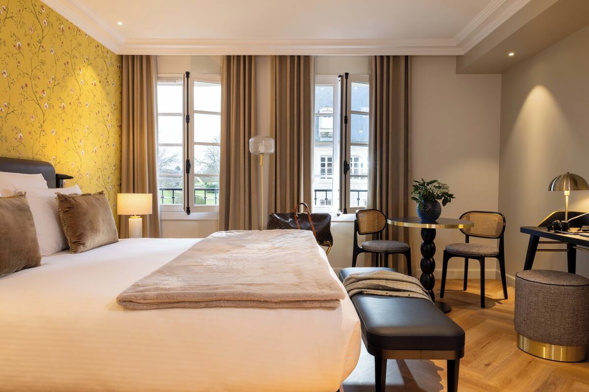 Une chambre d’hôtel avec un grand lit, un bureau, une chaise et une petite table.
