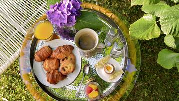 Un plateau de petit-déjeuner avec des croissants, une tasse de café, un verre de jus d’orange et un petit bol de fruits.