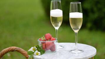 Two champagne glasses on a marble table with strawberries and a small bowl of strawberries.