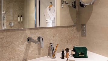 Un baño con lavamanos, espejo y artículos de aseo.