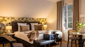 Une chambre d’hôtel avec un grand lit, un bureau, une chaise, une table et une fenêtre avec des rideaux.