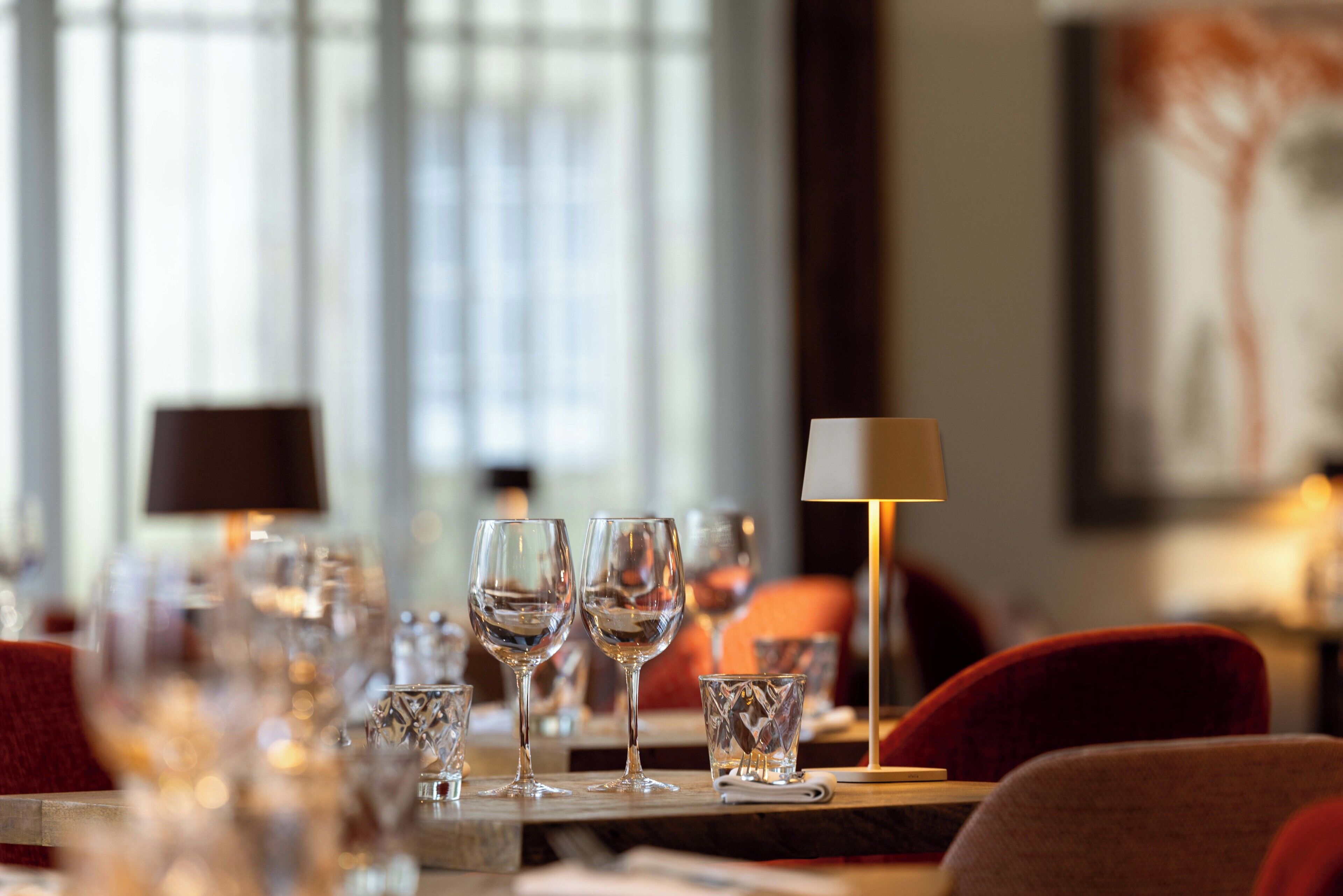 A dining table with multiple wine glasses and a lamp.
