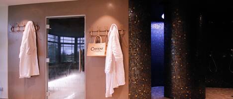A modern bathroom with a glass door, a towel rack, and a decorative mosaic wall.