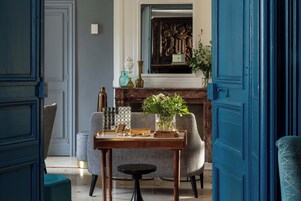 Un comedor con una mesa de madera, dos sillas grises, una mesita redonda y una puerta azul.