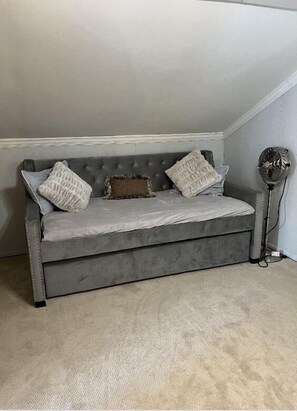 Relax on a tufted sofa with throw blanket and pillows, set against a neutral backdrop.