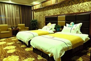 A hotel room with two beds, a sofa, a small table, and a decorative wall. - Jinyu Hotel (Zhaosu)
