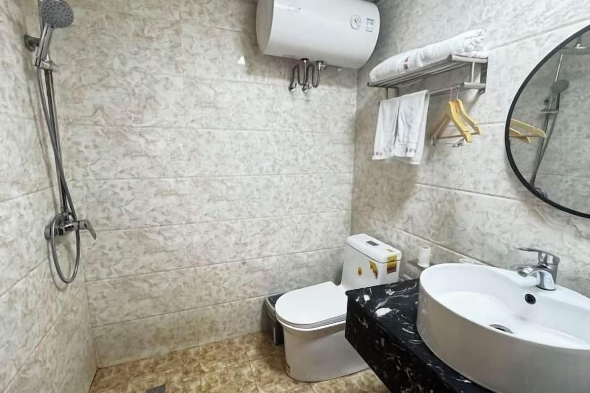A bathroom with a shower, toilet, sink, towel rack, and a mirror.