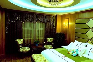 A hotel room with a bed, two armchairs, a small table with a plant, and a decorative wall panel.