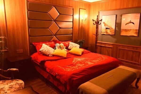 A bedroom with a large bed, wooden headboard, and two wall-mounted lamps. - Jinyu Hotel (Zhaosu)
