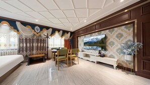 Habitación de hotel moderna con una cama grande, zona de comedor, televisor y un adorno en la pared.