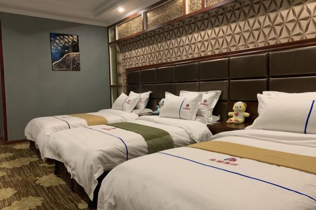A hotel room with two beds, a decorative headboard, a painting on the wall, and a plush toy on the nightstand.
