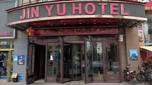 Entrada de un hotel con un letrero curvo que muestra el nombre 'JINYU HOTEL'.