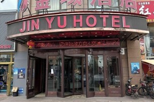 Entrada de un hotel con un letrero curvo que muestra el nombre 'JINYU HOTEL'.