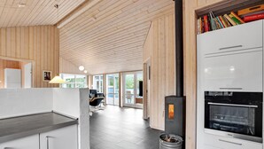 A modern kitchen with a wood-paneled ceiling, a built-in stove, and a white refrigerator. - Amazing home in ålbæk with sauna (Ålbæk)