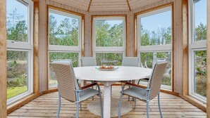 A round table with four chairs in a wooden-paneled room with large windows. - Amazing home in ålbæk with sauna (Ålbæk)