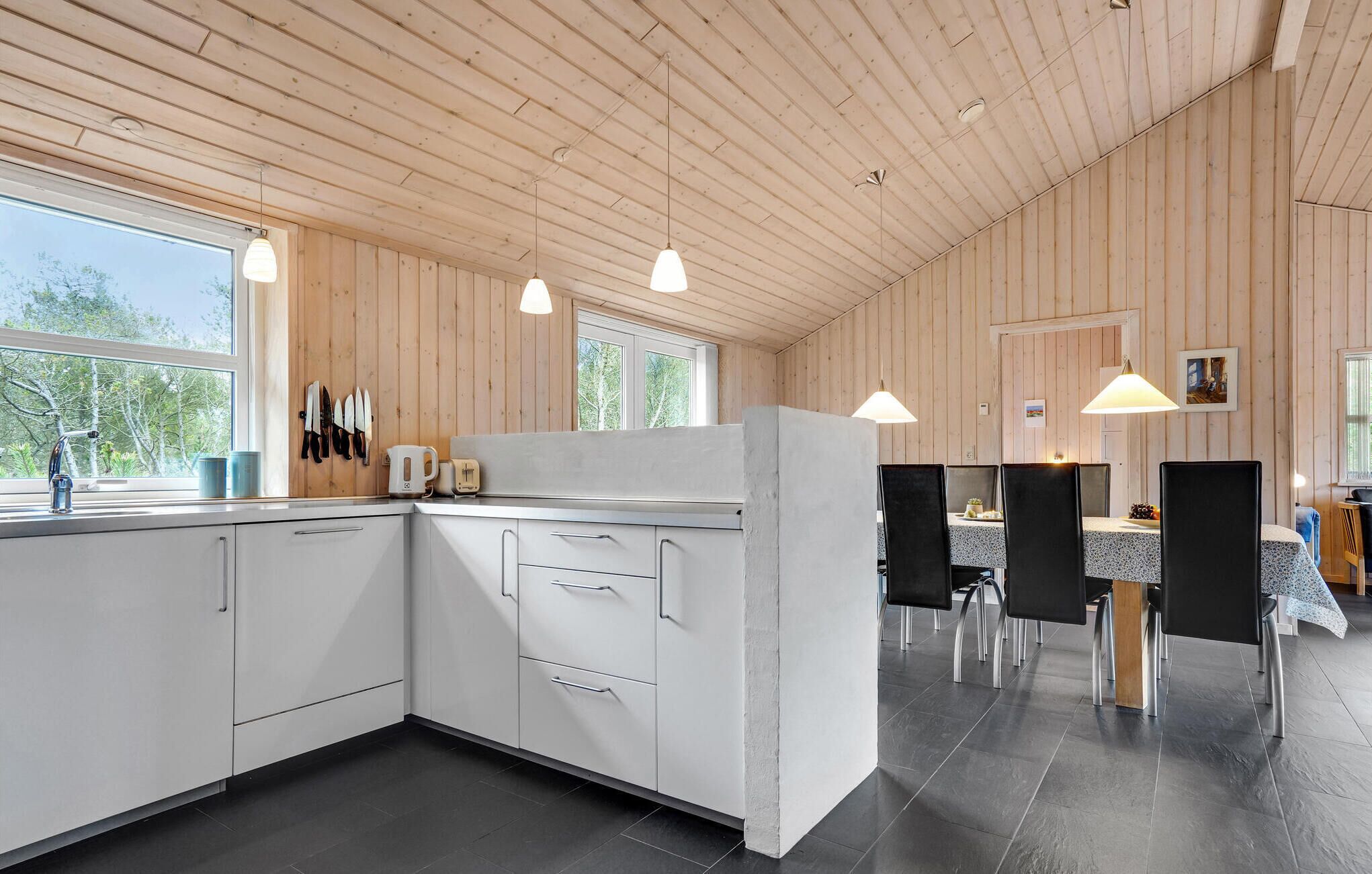 Una cocina moderna con armarios blancos, una isla grande e iluminación colgante.