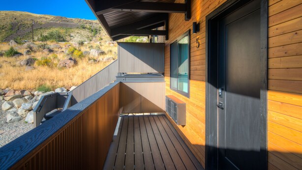 A wooden deck with a metal railing, a door, and a window. - Bison Meadow Lodge #5 (Gardiner)