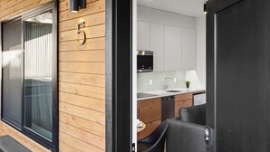 A modern kitchen with white cabinets, a black microwave, and a small table with a plant. - Bison Meadow Lodge #5 (Gardiner)