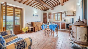 A rustic kitchen with wooden beams, a dining area with a table set for two, and a view through a glass door. - Pet friendly home in Cetona (Cetona)