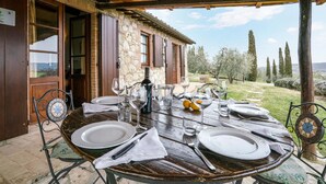 An outdoor dining area with a rustic stone building, a wooden pergola, and a view of the countryside. - Pet friendly home in Cetona (Cetona)