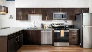 A modern kitchen with dark wood cabinets, stainless steel appliances, and a granite countertop.