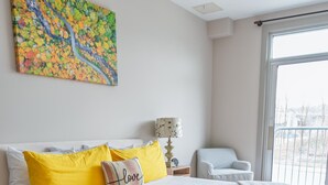 A bedroom with a large bed, a chair, a lamp, and a painting on the wall.