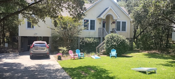 A two-story house with a front porch, a garage, and a lawn with outdoor furniture. - HEY, GET A ROOM! Couples Getaway : Bikes, beach chairs, umbrella :Central locale (Kitty Hawk)