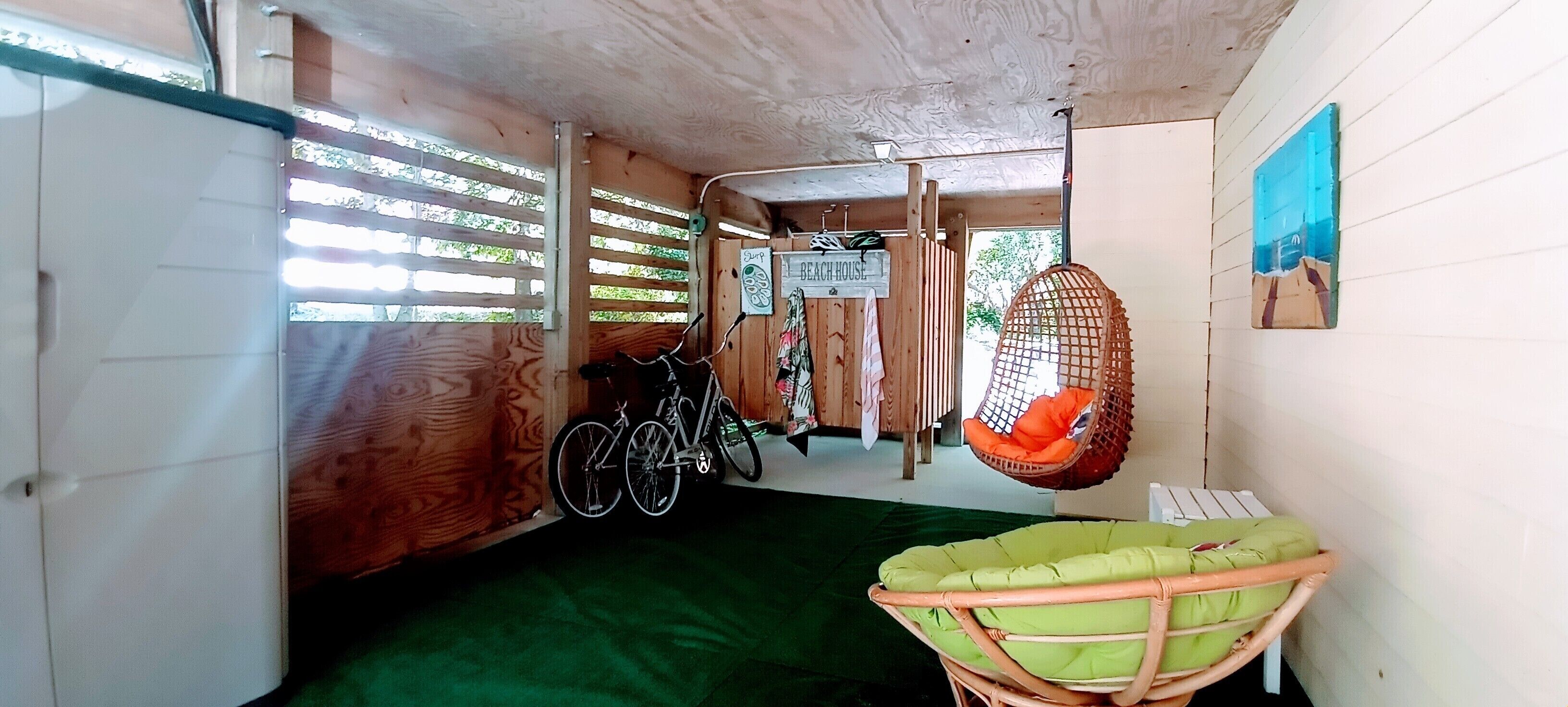 Ein Zimmer mit Holztür, einem Fahrrad, einem Hängesessel und einer grünen Matte auf dem Boden.