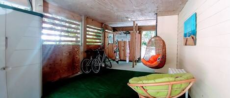 Ein Zimmer mit Holztür, einem Fahrrad, einem Hängesessel und einer grünen Matte auf dem Boden.