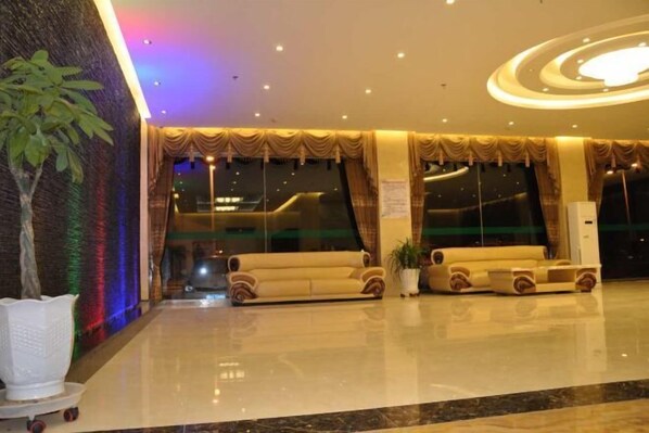 A lobby with a large sofa, a potted plant, and a wall with a textured pattern. - Yinhe Hotel (Duolun)