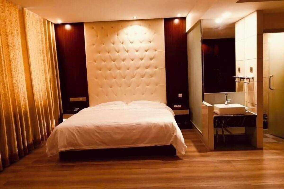 A bedroom with a bed, a bedside table, a mirror, and a built-in wardrobe.