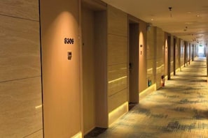 A hotel corridor with doors marked with room numbers, a patterned carpet, and a fire extinguisher on the wall. - Yinhe Hotel (Duolun)