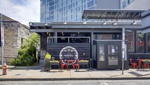 A hotel with a modern exterior, a sign indicating the address, and outdoor seating with red chairs. - Center Gulch - Walk to Downtown - Private Parking (Nashville)