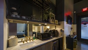 A modern kitchen with a sink, stove, and coffee maker. There is a mirror above the sink, and a plant on the countertop. - Center Gulch - Walk to Downtown - Private Parking (Nashville)