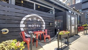 A small, modern hotel with a wooden facade and a sign that reads "HOTEL." There are red chairs and a small table outside, with a rope barrier in front. - Center Gulch - Walk to Downtown - Private Parking (Nashville)