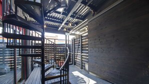 A spiral staircase in a modern building with metal railings and a wooden deck. - Center Gulch - Walk to Downtown - Private Parking (Nashville)