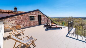 A brick building with a balcony, two lounge chairs, and a table. - Amazing home in Razanac (Razanac)
