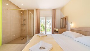 A hotel room with a bed, a bedside table, a mirror, a shower area, and a view of the outdoors. - Amazing home in Razanac (Razanac)