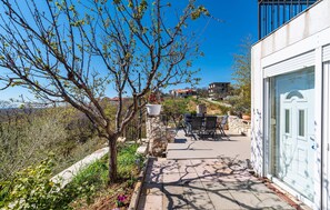 A balcony with outdoor furniture, a stone wall, and a view of buildings in the background. - Amazing home in Razanac (Razanac)
