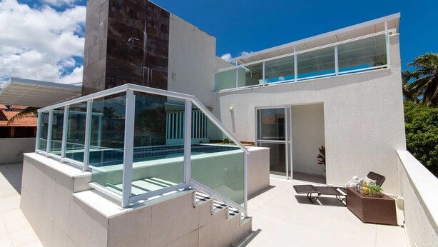 Un edificio moderno con balcón de vidrio y piscina.