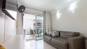 Una sala moderna con un sofá, un ventilador y un ventanal corredera que da a un balcón.