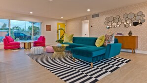 A modern living room with a teal sofa, red armchairs, and a black and white striped rug. - Located in the famous Movie Colony neighborhood close to Downtown. (Palm Springs)