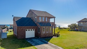A two-story house with a garage, a balcony, and a view of the ocean.