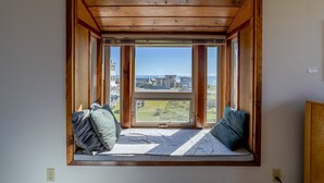 A room with a built-in window seat featuring a view of a residential area and a body of water.