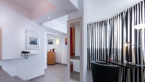 A modern hotel room with a dining area, a mirror, a phone, and a view of the hallway. - Turmhotel Rhein Main (Dreieich)