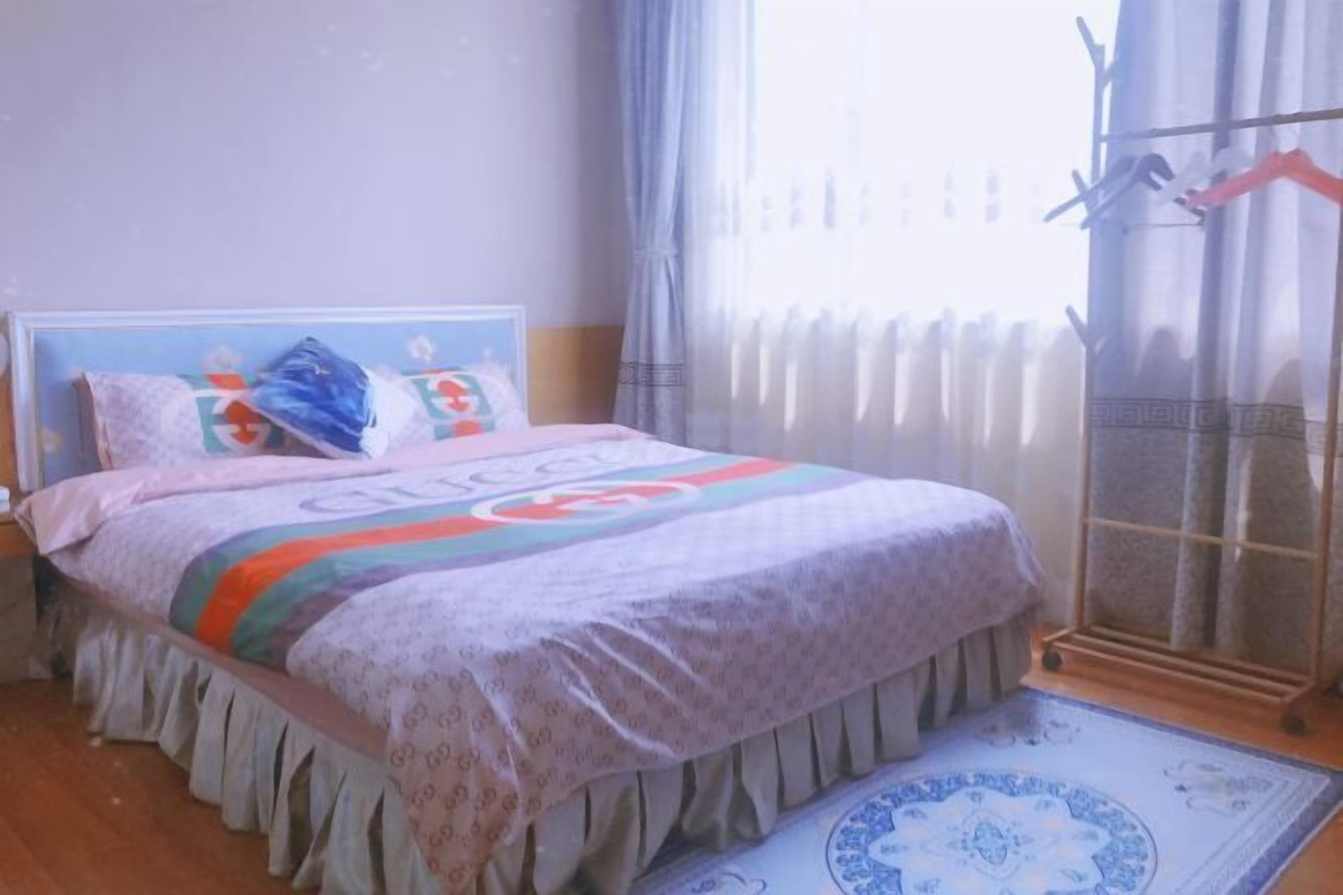 Un dormitorio con cama, ventana con cortinas y radiador.
