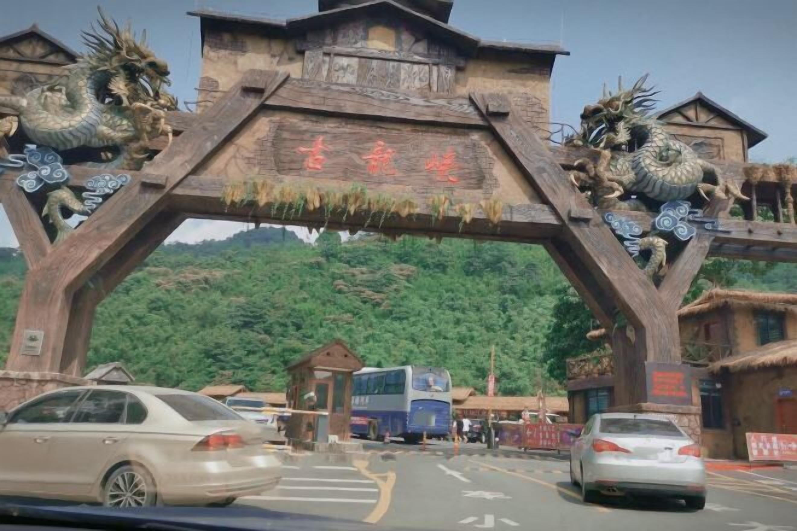 A wooden archway with dragon sculptures and a sign.