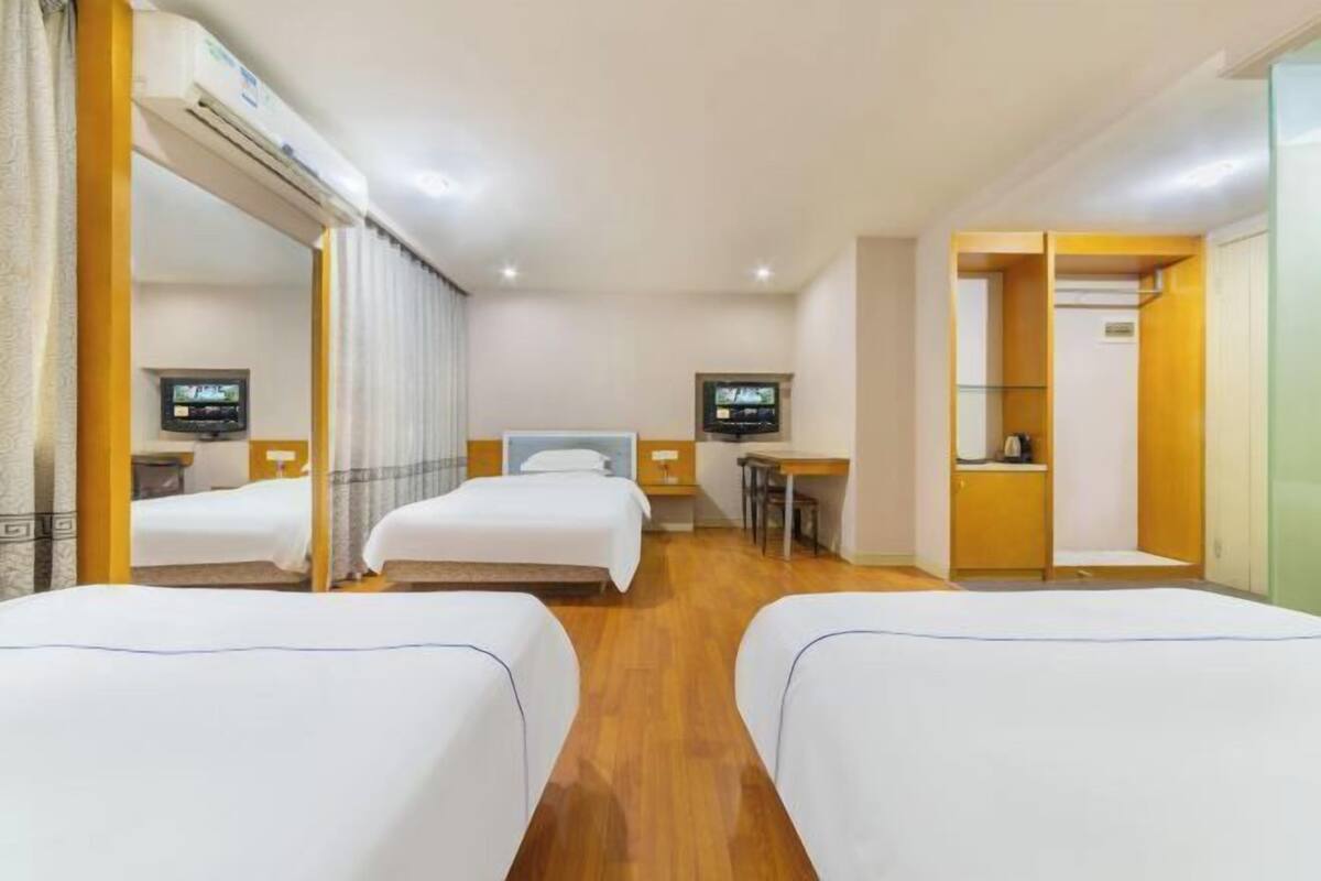 Een hotelkamer met twee bedden, een bureau, een stoel, een televisie en een kledingkast.