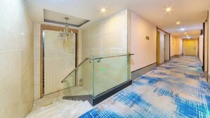 Een hotelhal met glazen balustrade, betegelde wanden en een kamerbreed tapijt.